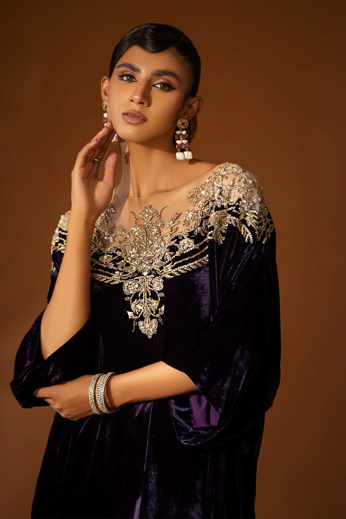 Purple velvet kaftan with embellished nude net neckline, short side slits, and gold jamawar pants with tissue finish – perfect for winter events 2025.