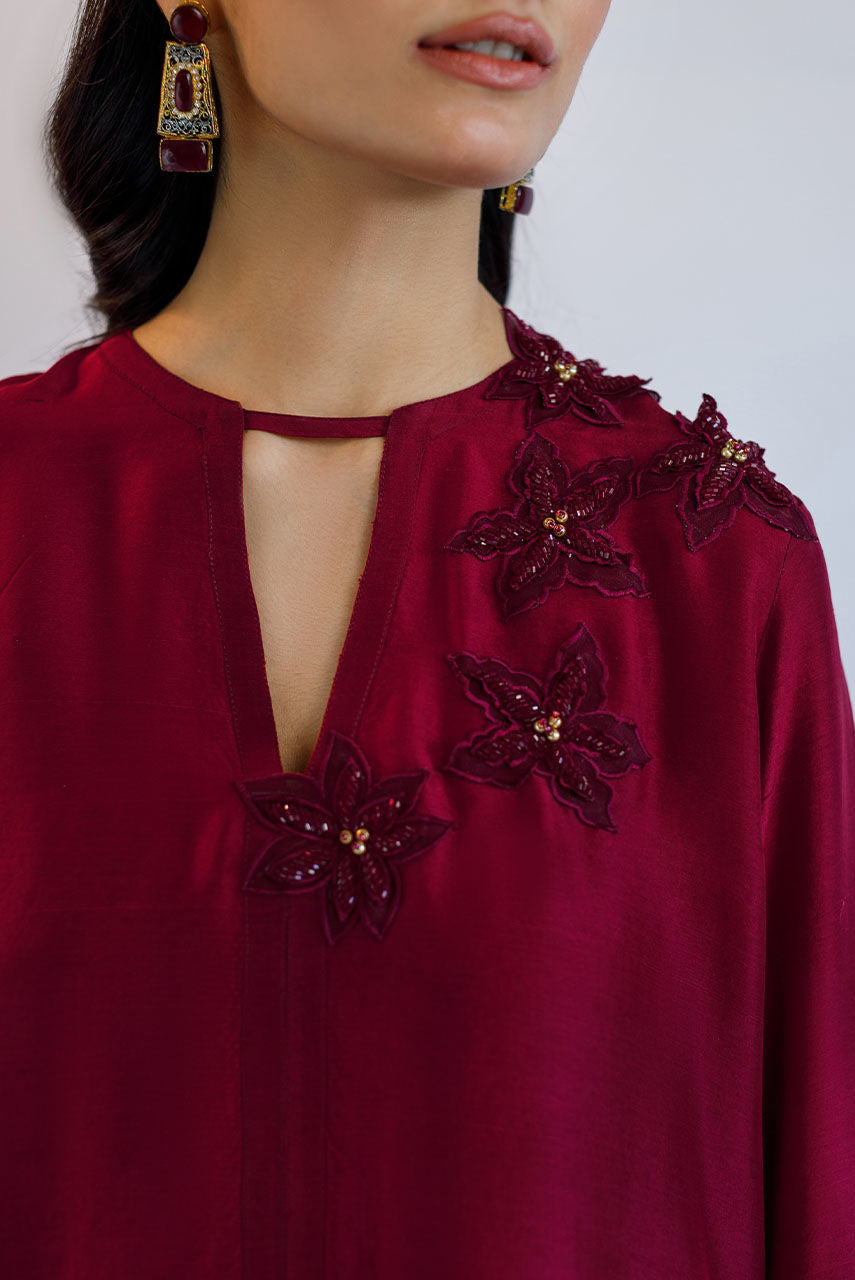 Maroon raw silk Pakistani party dress with 3D floral embroidery, katdana work, and lace finishing – custom stitched for weddings and formal events.