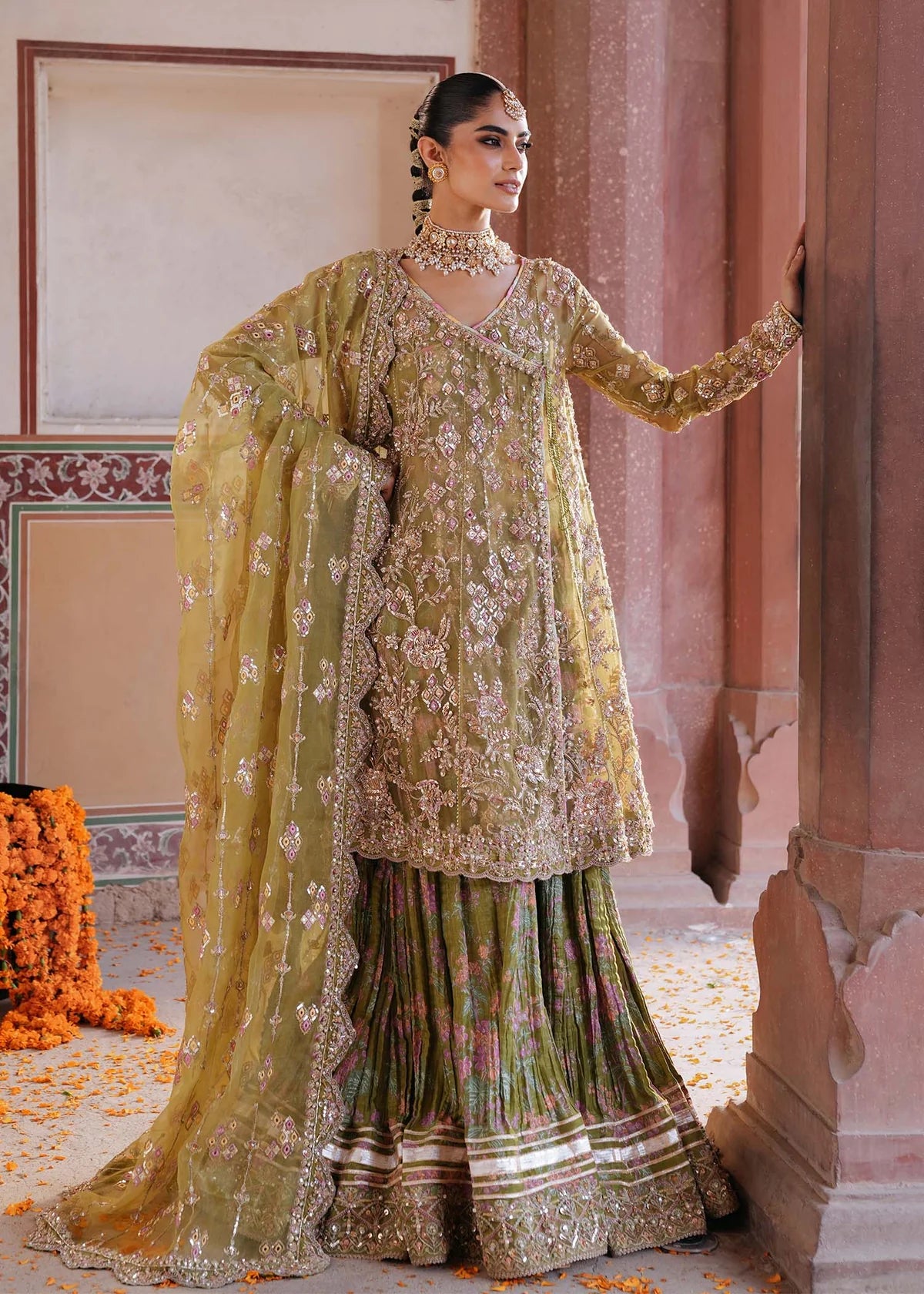 AMAL – Olive green angrakha style sharara suit with embroidered organza top, printed crushed sharara, and dupatta. Online at Pakistanimoda.