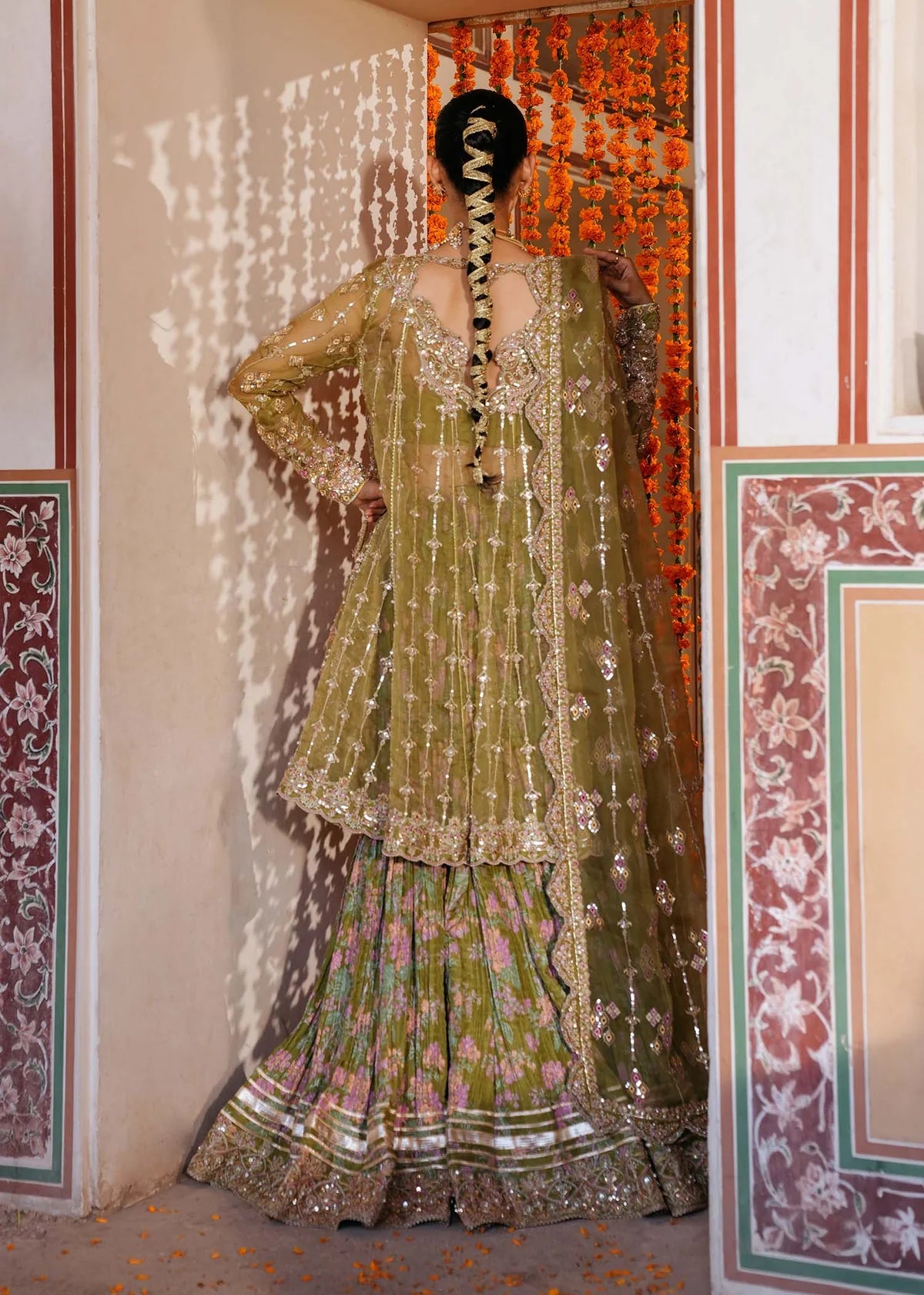 AMAL – Olive green angrakha style sharara suit with embroidered organza top, printed crushed sharara, and dupatta. Online at Pakistanimoda.