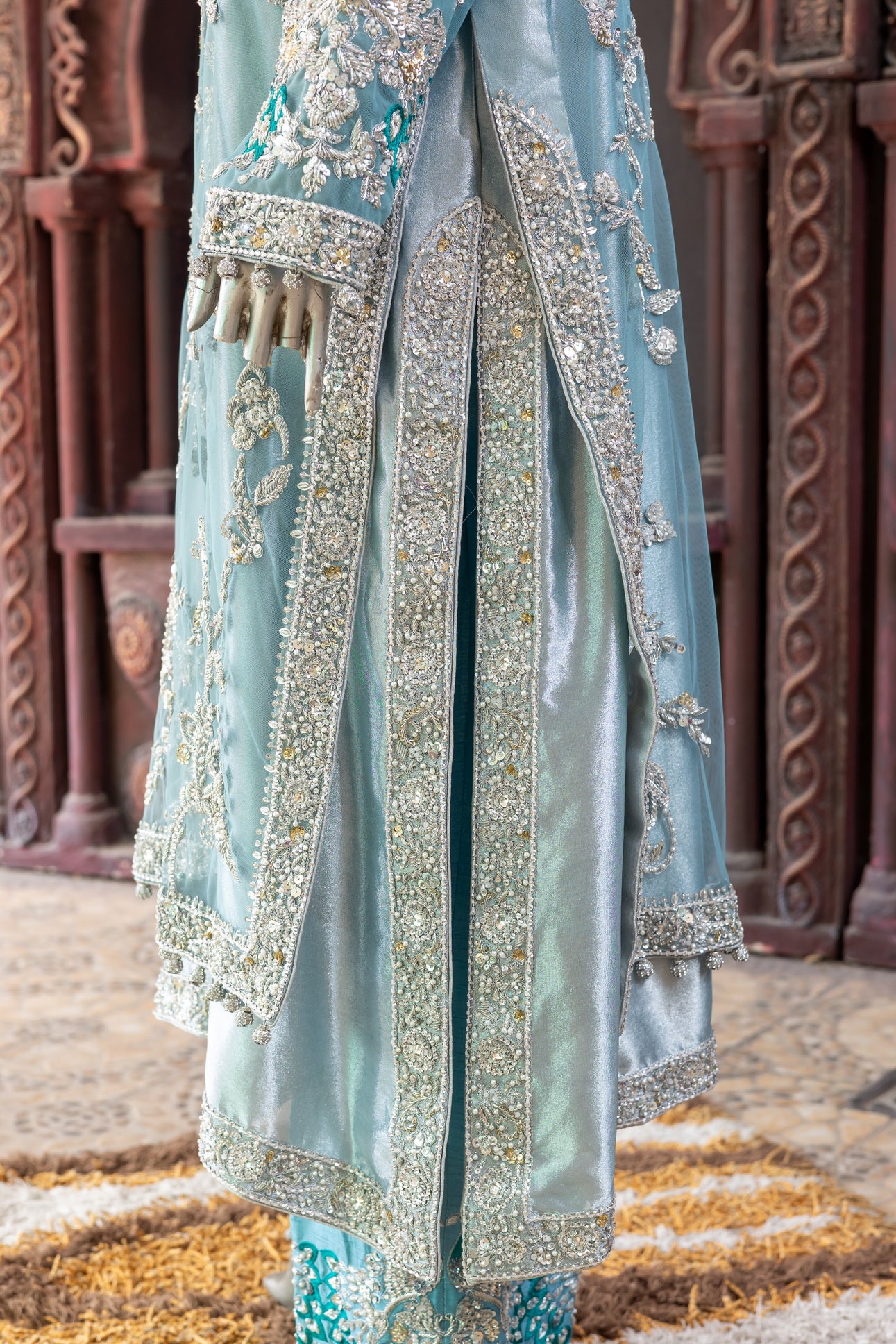 Teal Pakistani formal suit by MariamRaj featuring hand-embellished net shirt with zari, mirror work, pearls, and sequins, paired with tissue inner, embroidered pants, and a net dupatta.