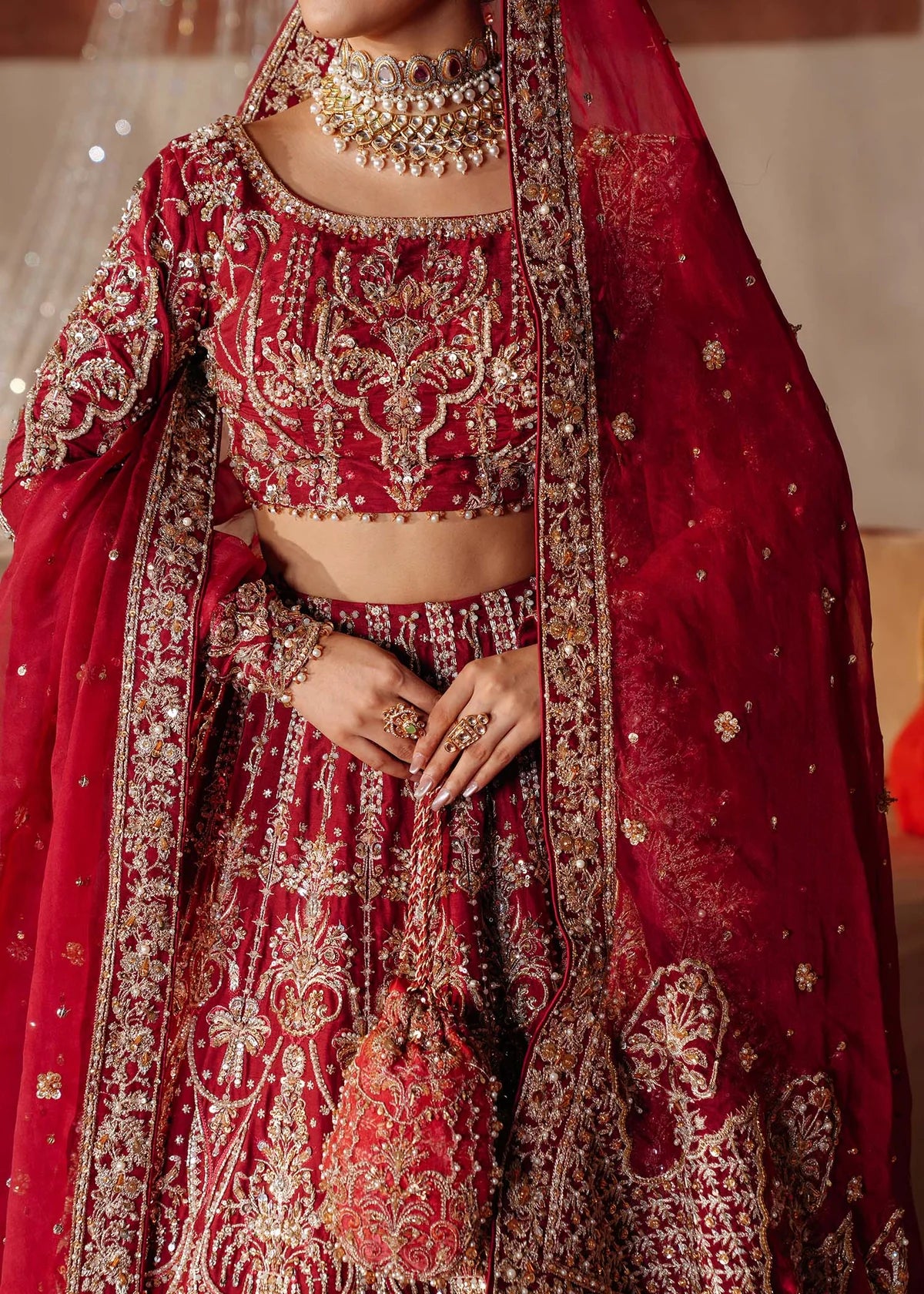 KRISHAM – Red bridal lehenga choli in Korean silk with organza dupatta and heavy embroidery. Stitched bridal outfit online at Pakistanimoda.