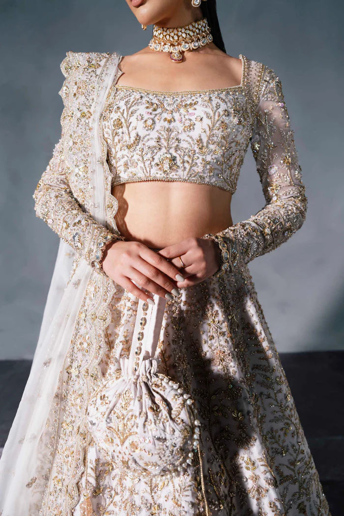 White and gold Pakistani bridal lehenga with floral embroidery, full sleeves, and sheer dupatta – perfect for South Asian weddings abroad.