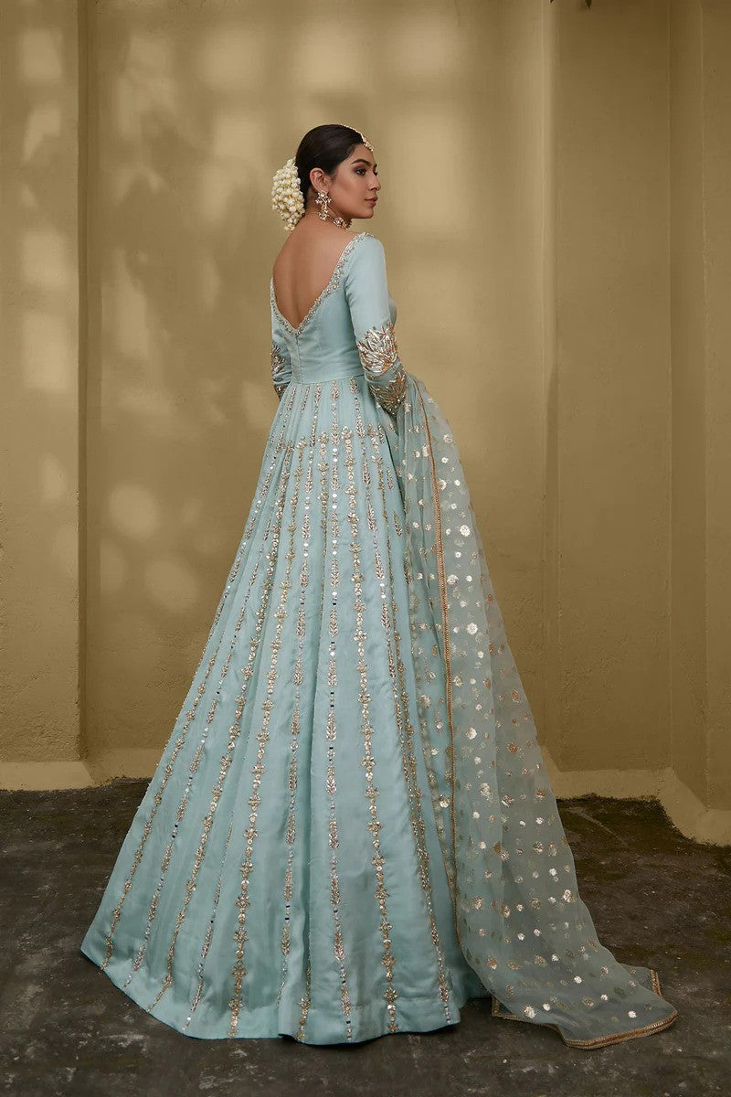 Sky blue silk chiffon gown with embellished neckline, floral sleeves, gota and mirror work, paired with zari organza dupatta – ideal for Pakistani weddings and formal events.