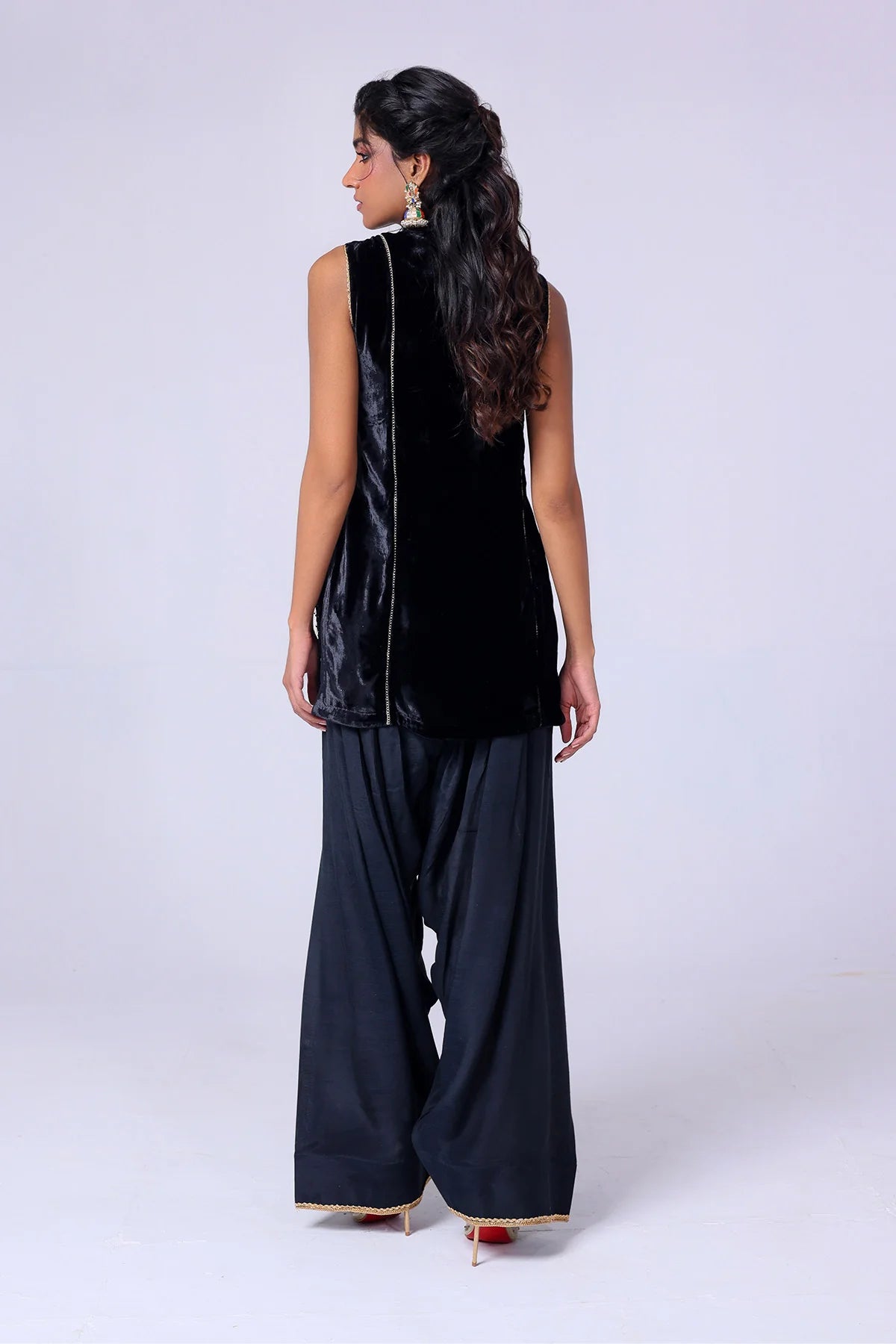 Black velvet sleeveless shirt with gold embroidery, wide raw silk shalwar, and organza dupatta – Pakistani festive outfit at Pakistanimoda