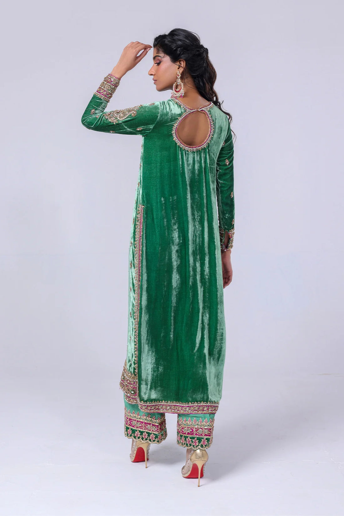 Green velvet shirt with keyhole neckline, naqshi and dabka handwork, silk pants with embellished hem, and matching organza dupatta – festive wear 2025.

