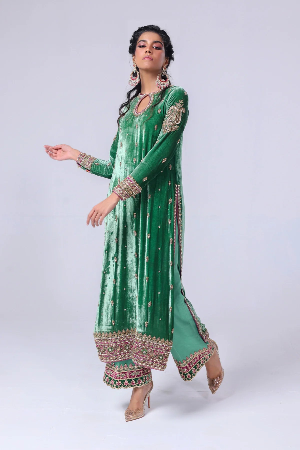 Green velvet shirt with keyhole neckline, naqshi and dabka handwork, silk pants with embellished hem, and matching organza dupatta – festive wear 2025.


