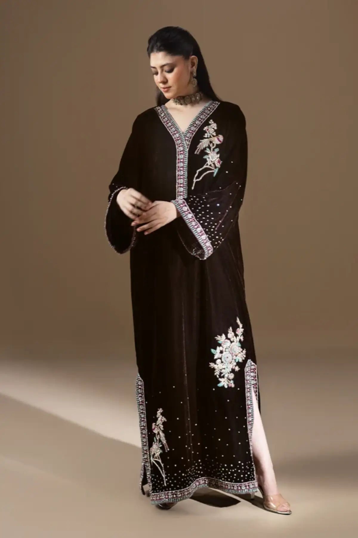 Nocturne dark chocolate brown shiny velvet stitched kaftan with pastel resham floral embroidery, silver detailing, sequin embellishments and V-neckline.