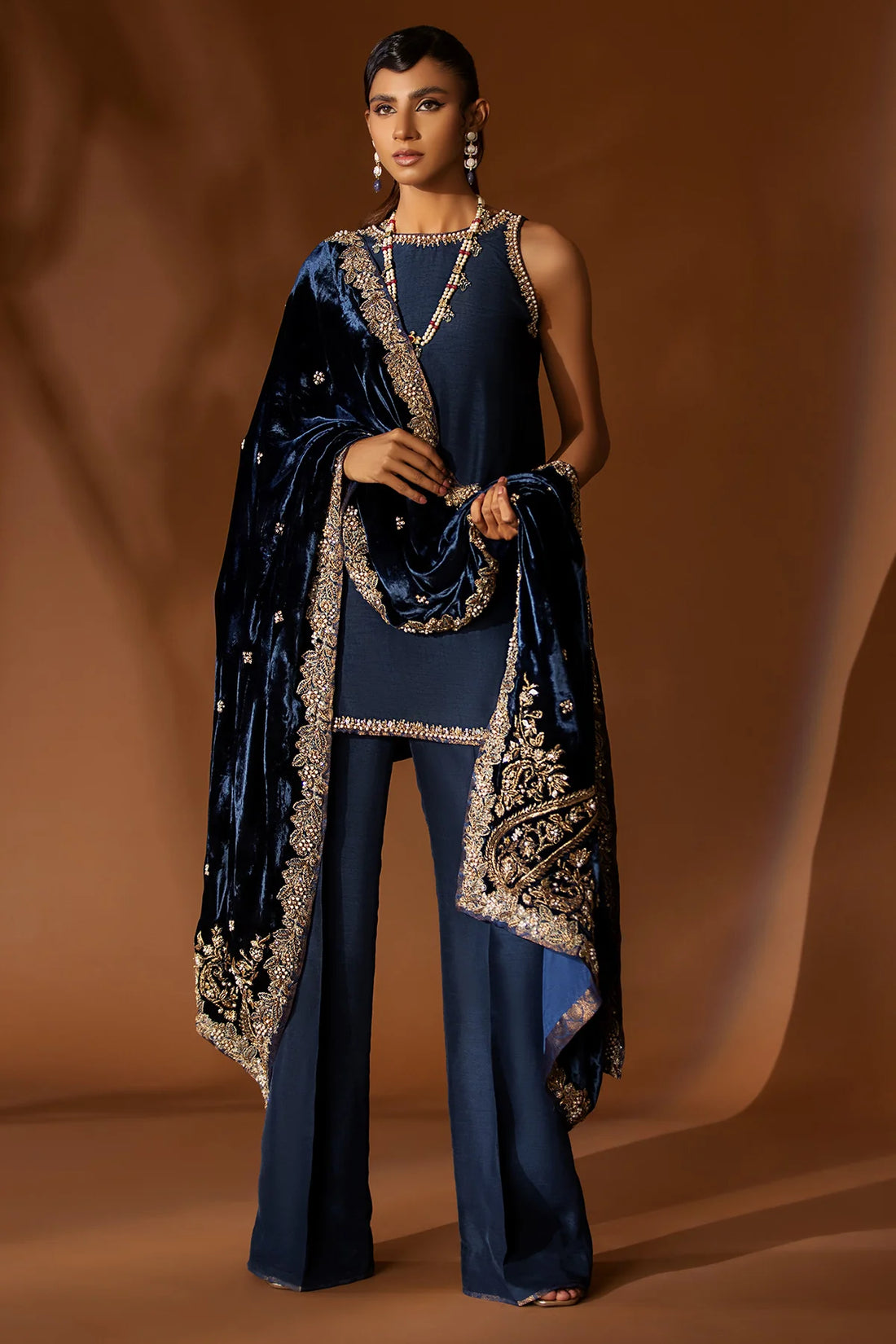 Navy blue formal outfit with hand-embellished raw silk shirt, bootcut pants, and embroidered velvet shawl – Eid wear for women from Pakistanimoda