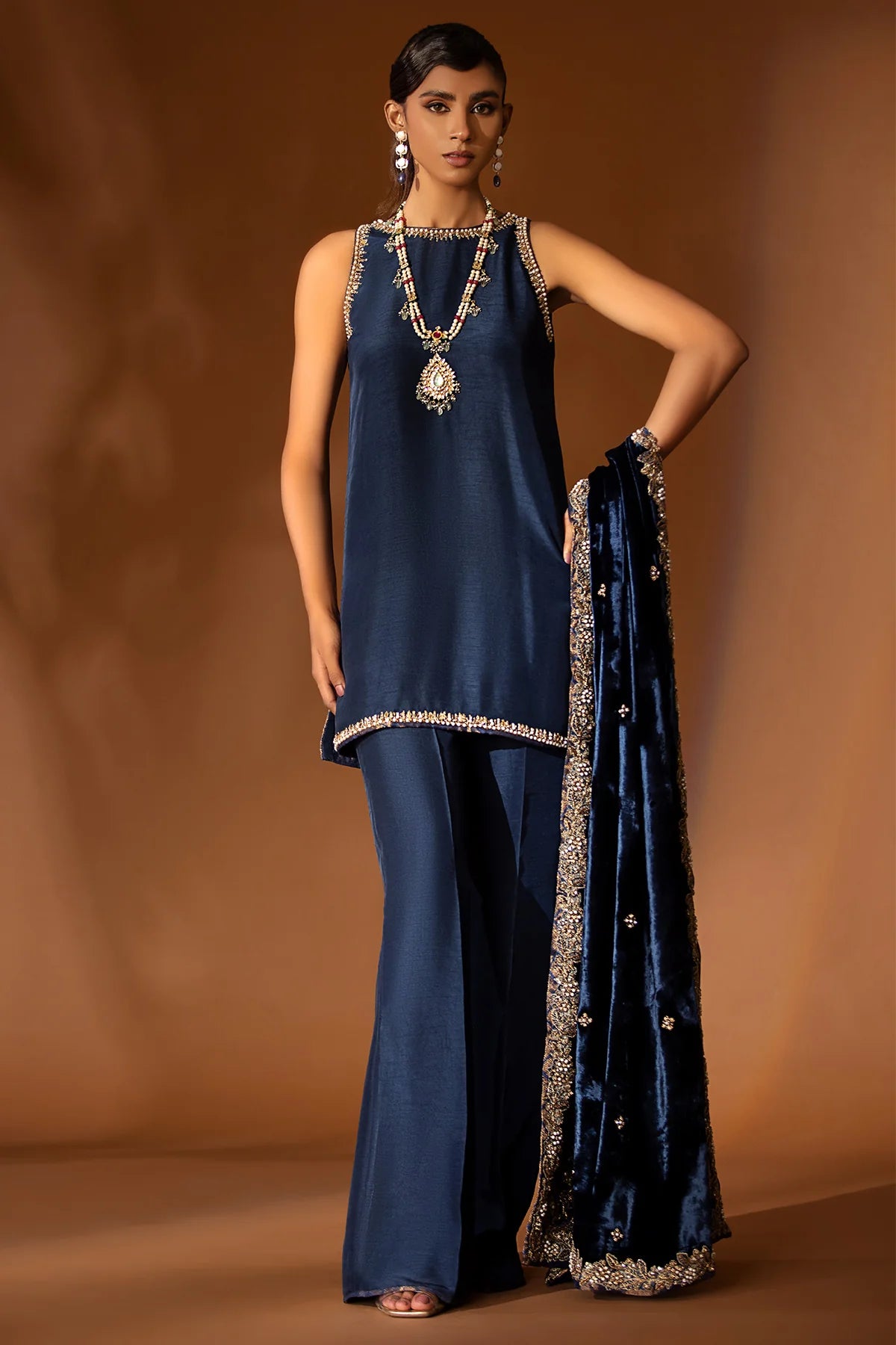 Navy blue formal outfit with hand-embellished raw silk shirt, bootcut pants, and embroidered velvet shawl – Eid wear for women from Pakistanimoda
