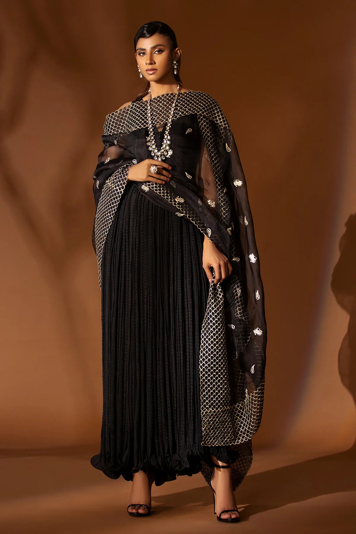 Black pleated silk outfit with gold embroidered organza dupatta – festive formal wear for women at Pakistanimoda