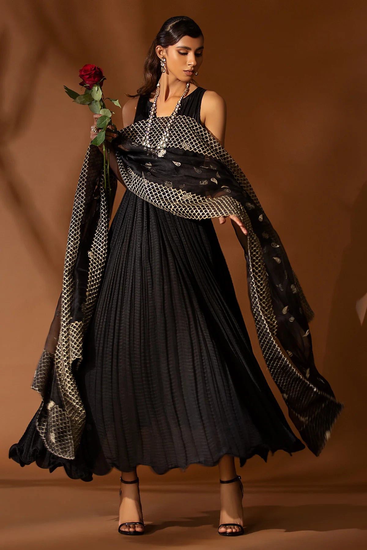 Black pleated silk outfit with gold embroidered organza dupatta – festive formal wear for women at Pakistanimoda