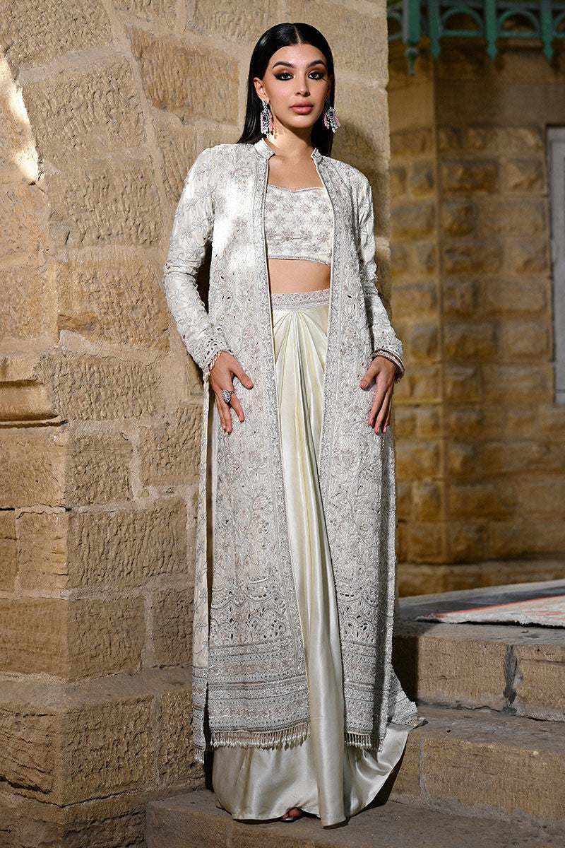 Designer ivory raw silk outfit with a structured cutwork jacket, shamooz silk draped skirt, and bandeau – modern Pakistani formal wear for weddings in USA, UK, and Canada.