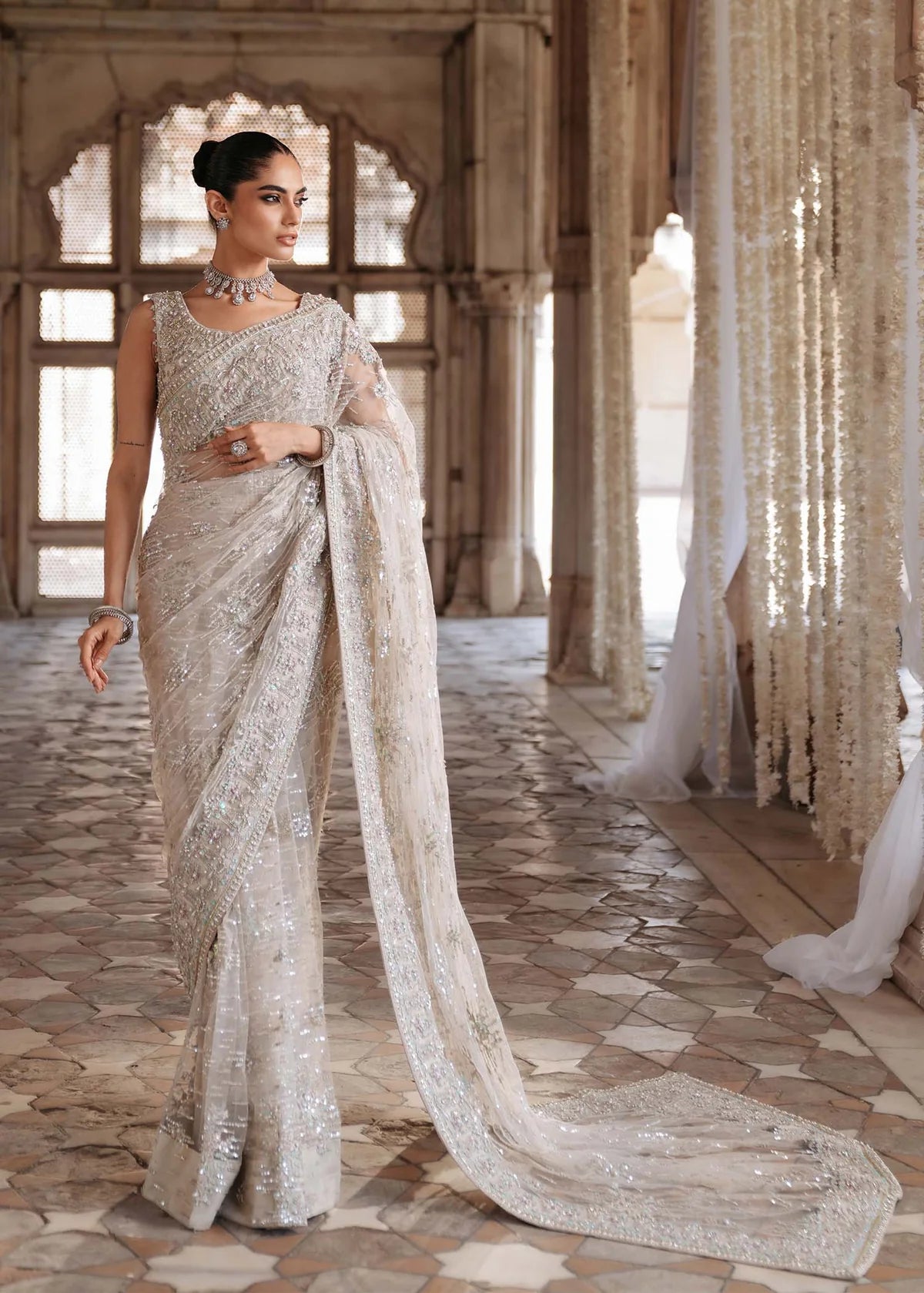 SIRAH – Ivory embroidered net saree with sequins, raw silk petticoat, and hand-embellished blouse. Stitched bridal saree online at Pakistanimoda.
