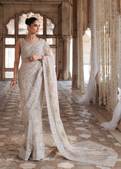 SIRAH – Ivory embroidered net saree with sequins, raw silk petticoat, and hand-embellished blouse. Stitched bridal saree online at Pakistanimoda.