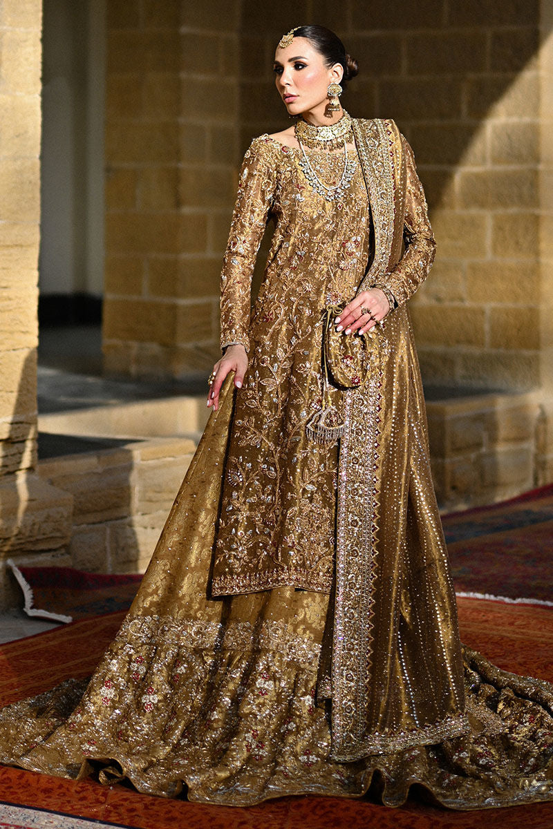 Gold Pakistani bridal ensemble with hand-embroidered zardozi, trailing silhouette, keyhole back, and maroon-accented dupatta – perfect for brides in USA, UK, and Canada.


