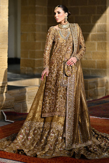 Gold Pakistani bridal ensemble with hand-embroidered zardozi, trailing silhouette, keyhole back, and maroon-accented dupatta – perfect for brides in USA, UK, and Canada.


