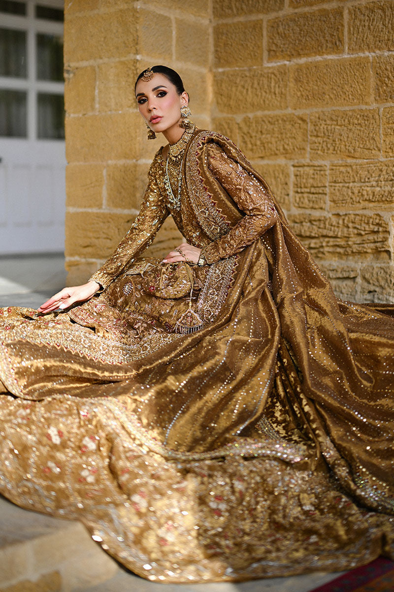 Gold Pakistani bridal ensemble with hand-embroidered zardozi, trailing silhouette, keyhole back, and maroon-accented dupatta – perfect for brides in USA, UK, and Canada.

