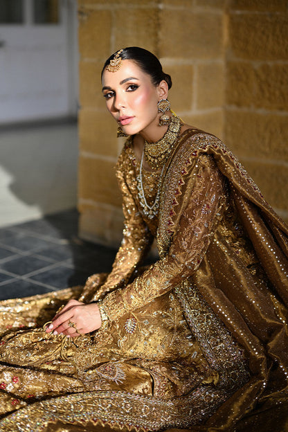 Gold Pakistani bridal ensemble with hand-embroidered zardozi, trailing silhouette, keyhole back, and maroon-accented dupatta – perfect for brides in USA, UK, and Canada.
