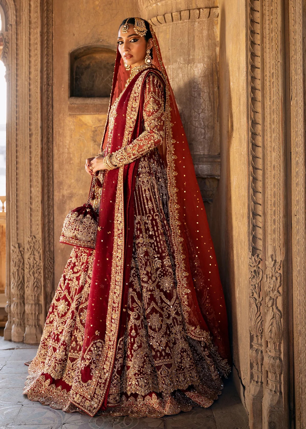 Shirin red stitched bridal pishwas and lehenga by Kanwal Malik with hand embellishments, paired with dual organza dupattas for wedding and festive events.