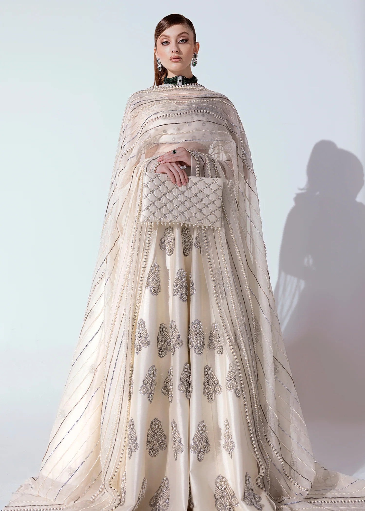 White and silver Pakistani lehenga choli with pearl, sequin, and bead embellishments, v-neck puffed sleeve choli, and an organza dupatta – ideal for weddings and formal events.