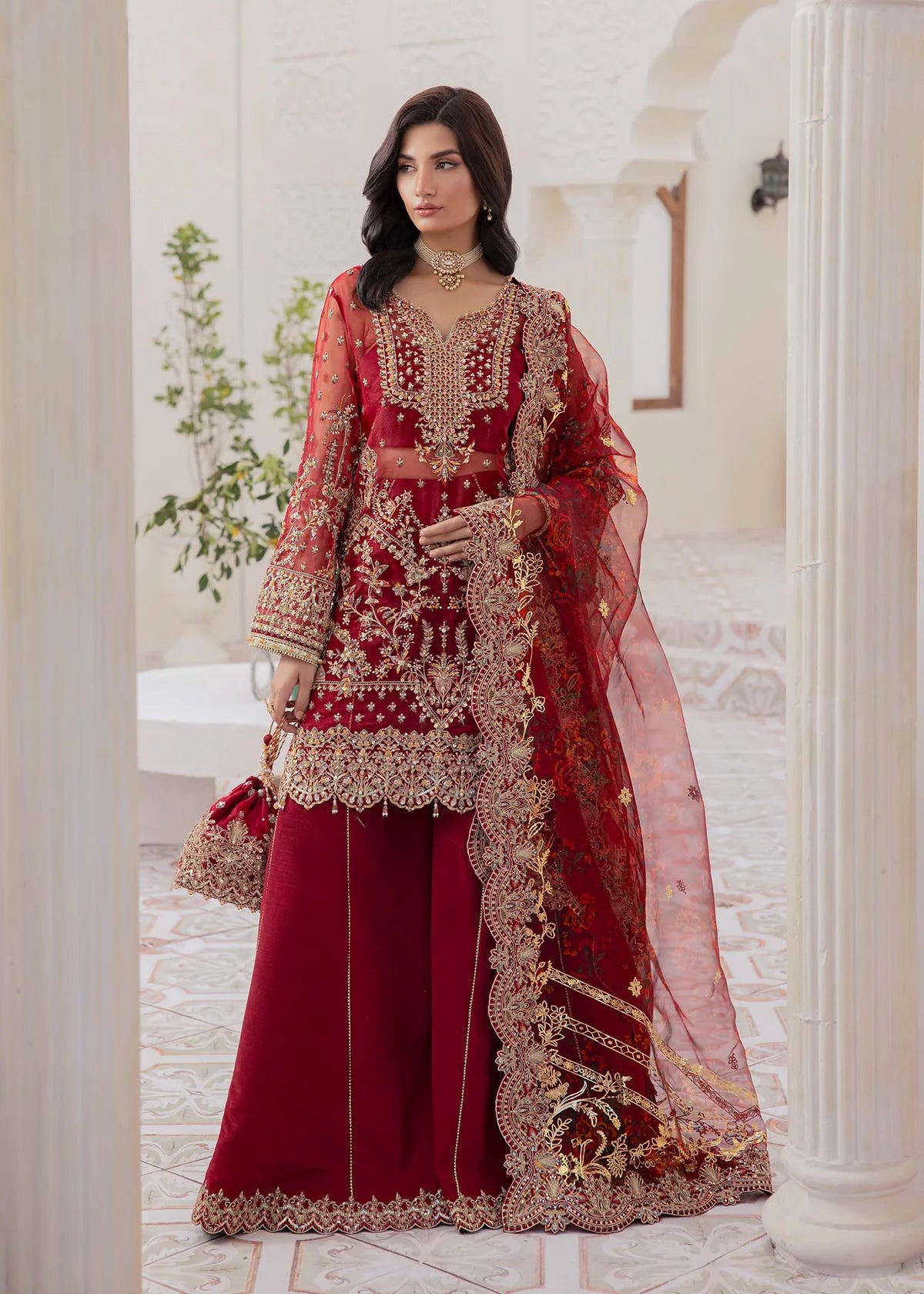 Red Pakistani flared pant suit with embroidered shirt, crystal embellishments, and printed foil dupatta – ideal for weddings and Eid events abroad.