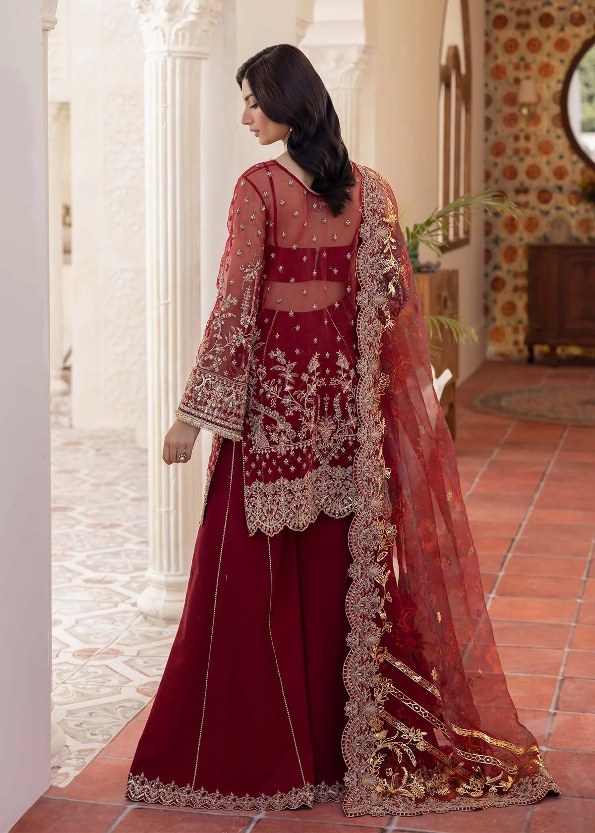 Red Pakistani flared pant suit with embroidered shirt, crystal embellishments, and printed foil dupatta – ideal for weddings and Eid events abroad.