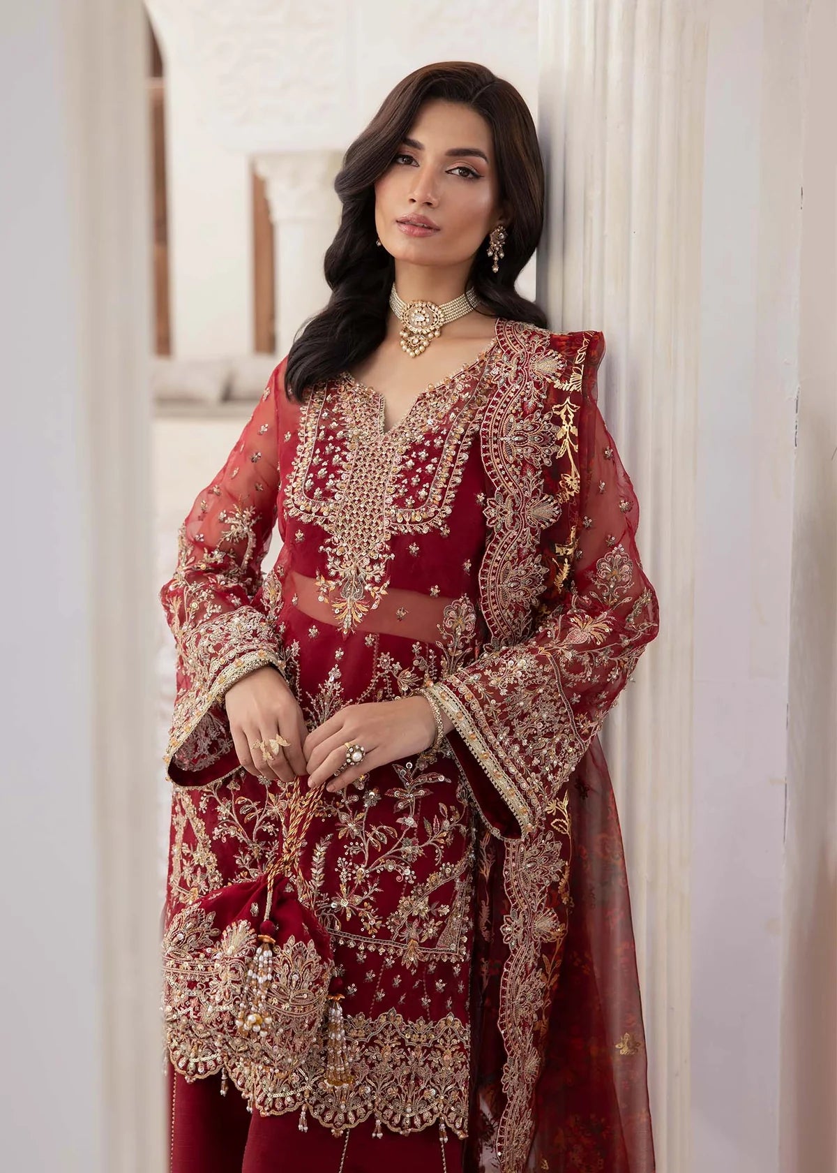 Red Pakistani flared pant suit with embroidered shirt, crystal embellishments, and printed foil dupatta – ideal for weddings and Eid events abroad.